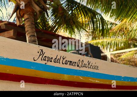 Farbenfrohes gestreiftes Boot unter Palmen an einem Strand in Playa del Carmen Stockfoto