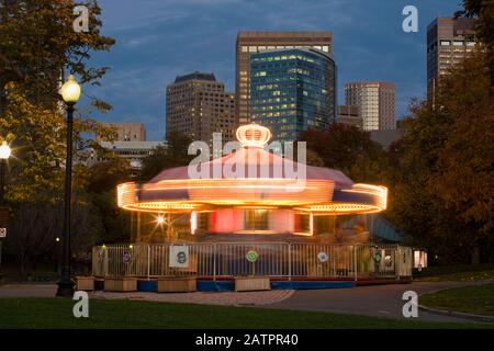 Verschwommenes Licht eines Karussells, das sich in der Dämmerung in einem Stadtpark dreht; Boston, Massachusetts, Vereinigte Staaten von Amerika Stockfoto