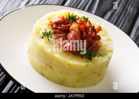 Kartoffelpüree und Grünkohl mit gebratenem Speck in einem Teller auf dem Tisch. Horizontal Stockfoto