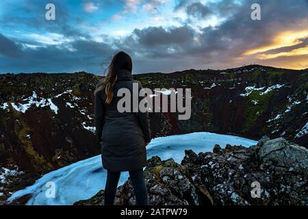 Frau, die auf der Klippe des Keritkraters in Island steht, wundert sich über Abenteuer auf Island Stockfoto