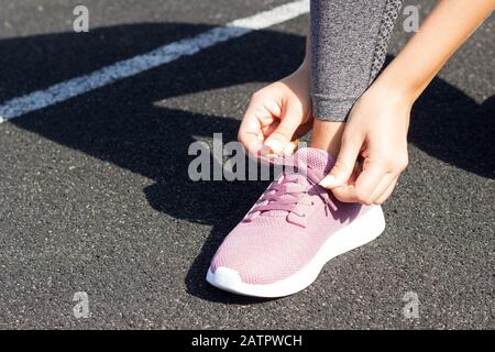 Bild von Fit Woman, die Schnürsenkel auf einer Laufstrecke im Stadion bindet. Sportlerin bereitet sich auf Leibesübungen und laufen vor. Stockfoto