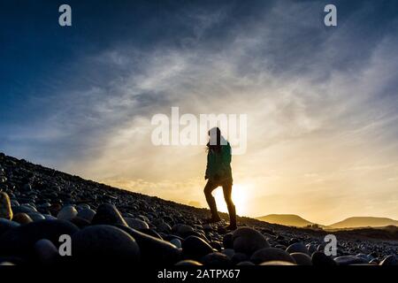 Ardara, County Donegal, Irland. Februar 2020. Low Winter Sonnenschein Silhouetten ein Wanderer auf dem "Wild Atlantic Way" Strand. Stockfoto