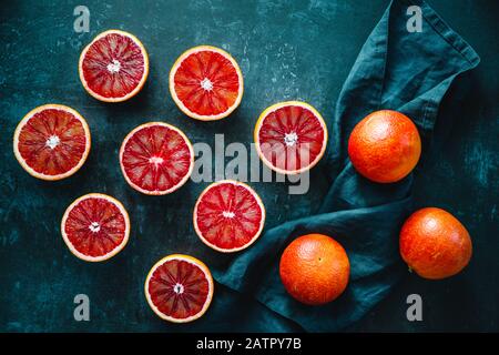 Flat Lay Food-Zusammensetzung mit geschnittenen Blutorangen auf dunkelblauem Hintergrund. Draufsicht. Stockfoto