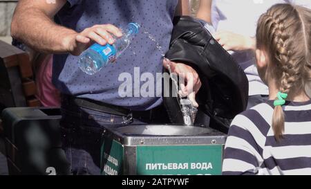 Moskau - Jule 24 2019: Männlich sammelt am 24. Juli 2019 in Moskau, Russland, Wasser aus dem Brunnen in einer Flasche zum Trinken. Stockfoto