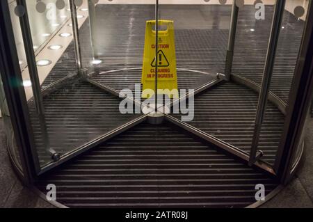 Gelbe Warnschild Reinigung im Gange in der Mitte von einigen Drehtüren eines Bürogebäudes. London Stockfoto