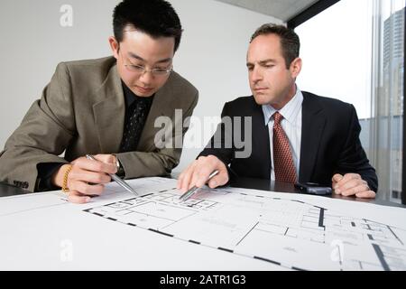 Zwei Architekten diskutieren auf Blaupausen in einem Büro. Stockfoto