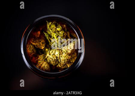 Cannabis Blumenknospen im Glasbecher, Top Down Close Up. Dunkler Hintergrund. Medizinisches Marihuana-Konzept. Stockfoto