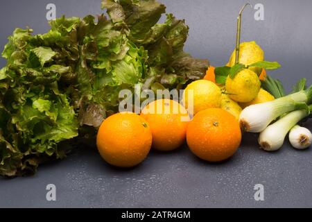 Obst, Orangen und Zitronen und Gemüse und Winter, Frühlingszwiebel und grüner Salat, Zitrusfrüchte, alle Bio, frisch aus dem Garten ausgewählt. Stockfoto