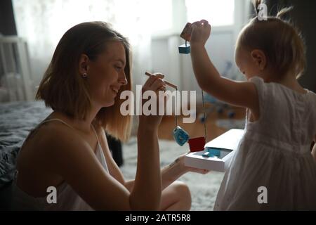 Mutter spielt mit ihrer kleinen Tochter im Zimmer auf dem Teppich. Stockfoto