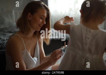 Mutter spielt mit ihrer kleinen Tochter im Zimmer auf dem Teppich. Stockfoto