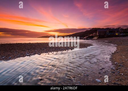 Charmouth, Dorset, Großbritannien. Februar 2020. Wetter in Großbritannien. Ein spektakulärer, feuriger Sonnenuntergang am Strand von Charmouth in Dorset mit Blick nach Westen entlang der Küste in Richtung Lyme Regis. Bildnachweis: Graham Hunt/Alamy Live News Stockfoto