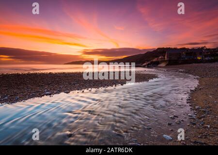 Charmouth, Dorset, Großbritannien. Februar 2020. Wetter in Großbritannien. Ein spektakulärer, feuriger Sonnenuntergang am Strand von Charmouth in Dorset mit Blick nach Westen entlang der Küste in Richtung Lyme Regis. Bildnachweis: Graham Hunt/Alamy Live News Stockfoto