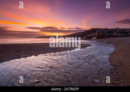 Charmouth, Dorset, Großbritannien. Februar 2020. Wetter in Großbritannien. Ein spektakulärer, feuriger Sonnenuntergang am Strand von Charmouth in Dorset mit Blick nach Westen entlang der Küste in Richtung Lyme Regis. Bildnachweis: Graham Hunt/Alamy Live News Stockfoto