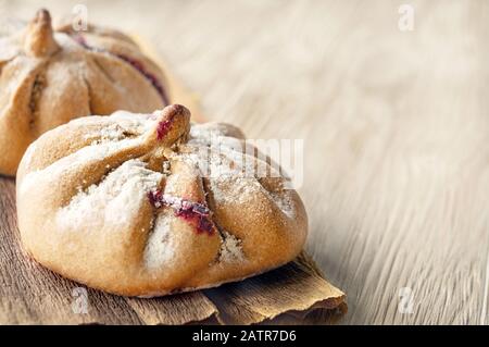 Brötchen aus Roggenmehl liegen auf einem hellen Holzhintergrund. Mexikanischer Todestag, Pan de Muerto. Kopierbereich. Stockfoto