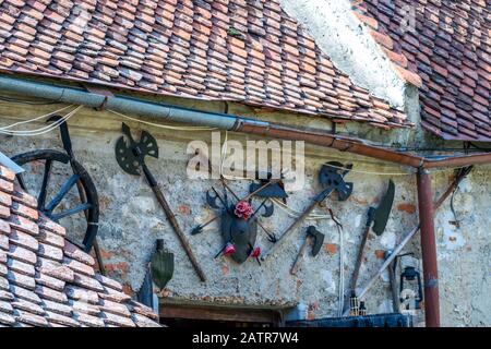 Foto von mittelalterlichen Waffen und Gegenständen, die an einer Wand am Eingang eines kleinen Museums in der Zitadelle Rasnov angebracht wurden - Rasnov, Brasov Country, Siebenbürgen Stockfoto