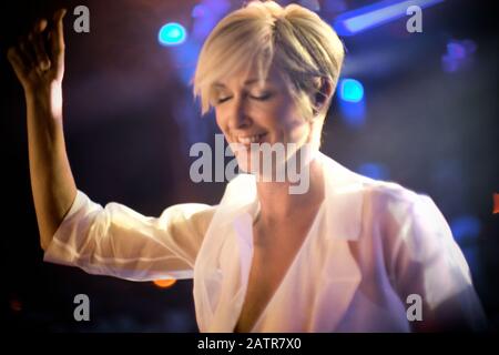 Junge Frau mit kurzen blonden Haaren, die Spaß beim Tanzen in einem Nachtclub mit geschlossenen Augen hat. Stockfoto