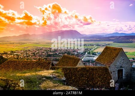 Foto der Stadt Rasnov bei Sonnenuntergang von der Zitadelle Rasnov aus gesehen - Rasnov, Brasov-Land, Siebenbürgen, Rumänien. Stockfoto