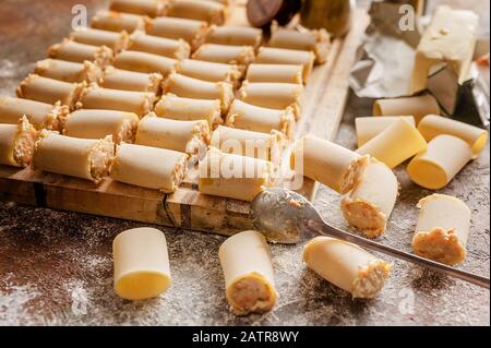 Rohe gefüllte Pasta mit Hackfleisch auf einer Holzschneideplatte. Italienische Cannelloni. Traditionelle Mediterrane Küche Stockfoto