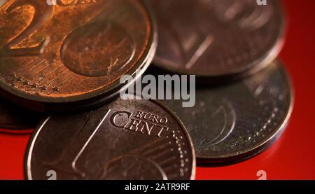 Makro Nahaufnahme der Kupfermünzen von Stapel eins und zwei Euro Cent auf glänzendem rotem Hintergrund Stockfoto