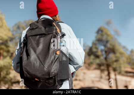 Junge Frau kleidete sich lässig mit Rucksack im Wald hoch in den Bergen auf den vulkanischen Felsen Stockfoto