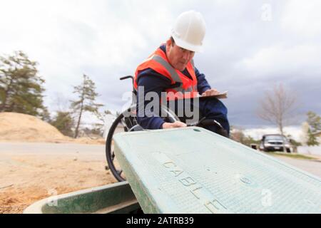 Mann im Rollstuhl, der an Erdkabeln arbeitet Stockfoto