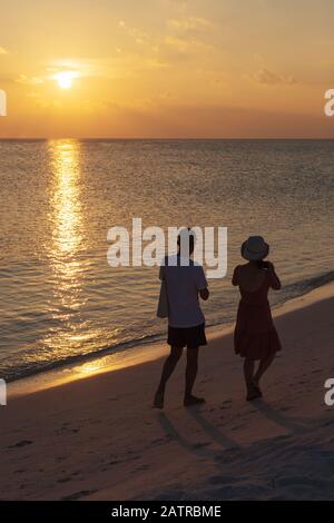 Ein Paar am Strand - ein Paar, das an einem tropischen Strand spazieren geht und den Sonnenuntergang über dem Indischen Ozean, den Malediven, Asien beobachtet Stockfoto