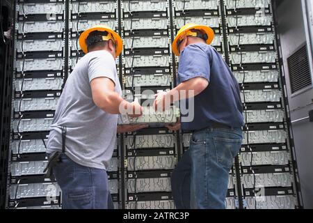 Zwei Auftragnehmer, die eine Komponente von einer Wand entfernen Stockfoto