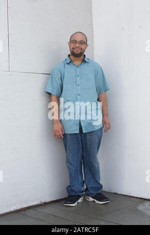Porträt eines jungen Mannes mit Down-Syndrom im Stehen Eine Ecke mit Blick auf die Kamera Stockfoto
