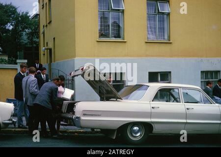 Ein Bild der Umgangssprache, das auf einer analogen 35-mm-Filmtransparenz aufgenommen wurde, glaubte, den Mann in einer schwarzen Jacke neben weißem Auto und Ladetrunk während des Tages, 1970, darstellen zu können. Zu den Hauptthemen/Objekten, die erfasst wurden, gehören Auto, Fahrzeug, Kraftfahrzeug und Landfahrzeug. () Stockfoto