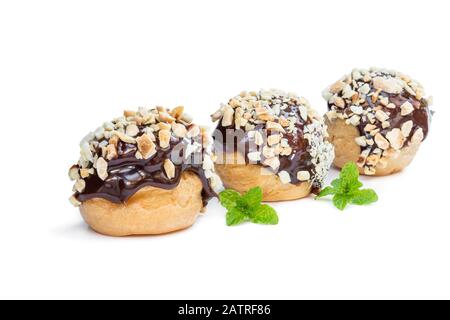 Hausgemachte Profiterolen mit Schokolade und gehackten Nüssen isoliert auf Weiß Stockfoto