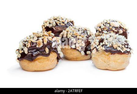 Hausgemachte Profiterolen mit Schokolade und gehackten Nüssen isoliert auf Weiß Stockfoto