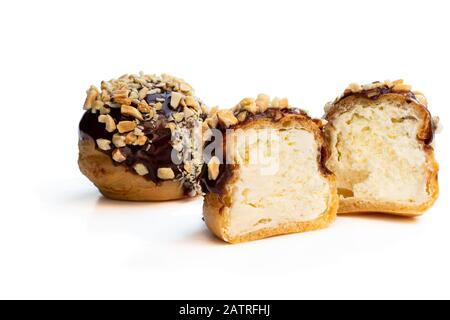 Hausgemachte Profiterolen mit Schokolade und gehackten Nüssen isoliert auf Weiß Stockfoto