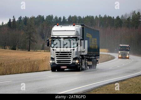 Zwei Lastwagen, Silver Scania R490 vor KW-Anhänger und Volvo FH, die am übergiebelten Tag Waren auf Landstraßen transportieren. Salo, Finnland. Januar 2020. Stockfoto