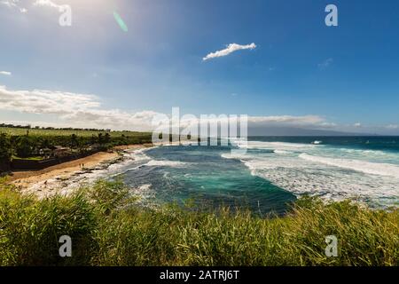 Üppiges grünes Laub und Blick auf die Wellen und den Ko'okipa Strand vom Ho'okipa Aussichtspunkt entlang der Nordküste, nahe Paia Stockfoto