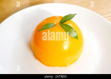 Mandarin Orange Dome-Cake in lebendigen Farben auf einem weißen Teller Stockfoto