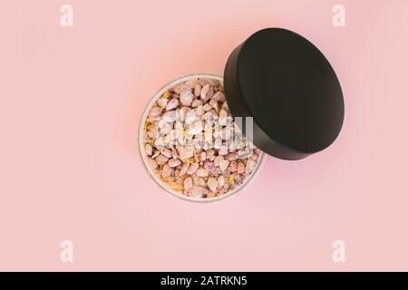 Natürliches Meersalz mineralische Körner in einem runden Behälter. Übersicht über den rosafarbenen Hintergrund. Flaches Lay mit Beauty-Produkt. Stockfoto