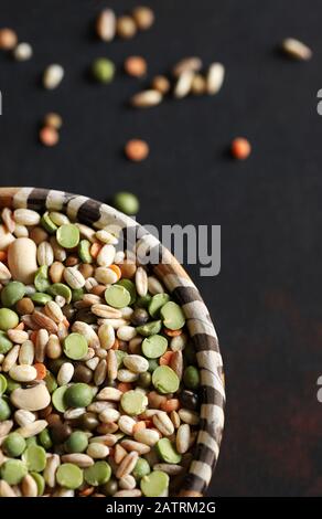 Gemischte getrocknete Hülsenfrüchte in der Schüssel isoliert auf dunklem Hintergrund.Draufsicht. Stockfoto