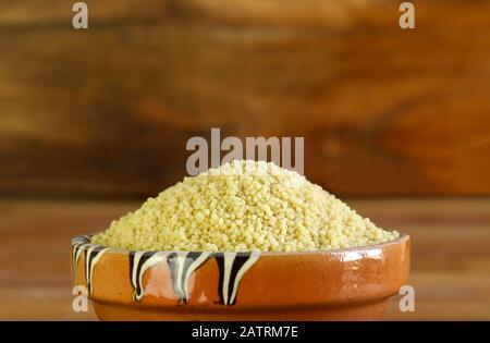 Nahaufnahme von Couscous in einer Schüssel auf Holztisch. Stockfoto