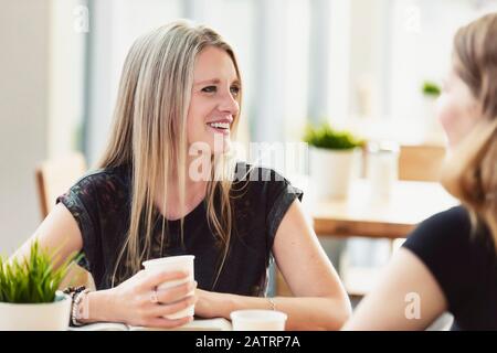 Eine reife christliche Frau, die bei einer jungen Frau in einem Café in Edmonton, Alberta, Kanada, ein Bibelstudium führt Stockfoto