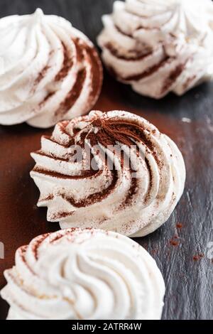 Vanille Meringue mit Kakaopulver auf schwarzem Hintergrund Stockfoto