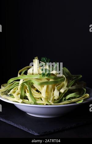 Konzept der italienischen Küche. Nahaufnahme des Gerichts mit Tagliatelle Pasta auf dunklem Hintergrund. Stockfoto