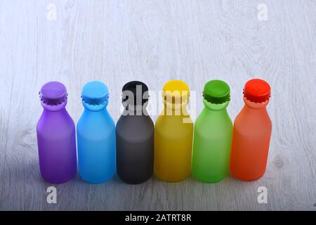Bunte alkoholfreie Getränke auf hellgrauem Hintergrund. Rainbow Composition and Getränkekonzept. Energy trinkt Behälter mit verschiedenen Geschmacksrichtungen auf Holztisch. Satz Flaschen in verschiedenen Farben. Stockfoto