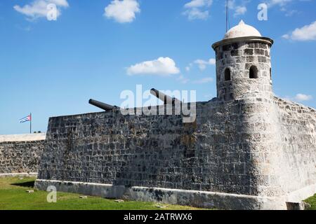 Kanonen über einer Steinmauer mit Wachturm, Castillo de San Salvador de la Punta, Central; Havanna, Kuba Stockfoto