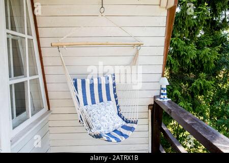 Blau und Weiß Gestreifte muster string und Baumwolle Hängematte Hängesessel, weiß lackierter Holzplatte Hintergrund. Entspannen in der Landschaft home Garten bal Stockfoto