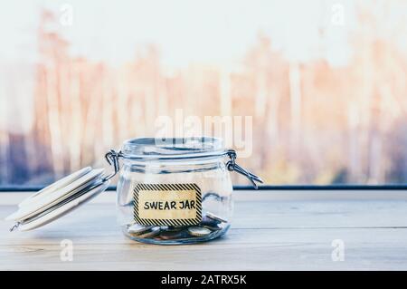 Selektive Fokussierung auf Glasbecher mit Text: Swear jar, darauf. Jedes Mal, wenn die Person verflucht oder schwört, muss sie Geld als Strafe in den Krug legen, damit sie sicher aufbewahrt wird. Stockfoto