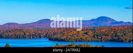 Herbstwald und Berge mit lebendigen Farben, Lake Memphremagog und Mount orford; Quebec, Kanada Stockfoto