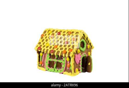Farbenfroh dekoriertes Lebkuchenhaus mit Icing- und Karamelglasfenstern, isoliert auf weißem Hintergrund. Stockfoto