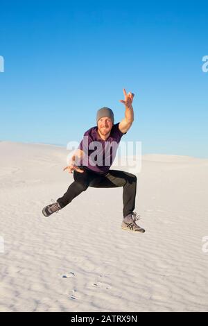 Sorgloser Mann in der Luft auf dem weißen Sand mit blauem Himmel, White Sands National Monument; Alamogordo, New Mexico, Vereinigte Staaten von Amerika Stockfoto