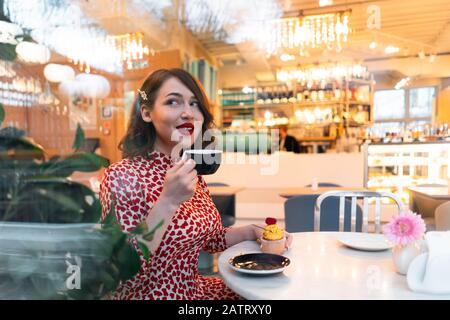 Schöne Brunette-Frau Feiert Allein Den Valentinstag Mit Cupcake Im Stilvollen Café. Selbstverständlichkeit Und Liebe Zu Sich. Stockfoto