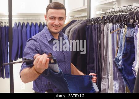 Mann wählt klassische Hose im Modegeschäft. Stockfoto